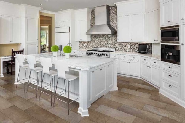 A kitchen with white cabinets and white countertops of mosaic tiles